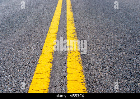 Yellow double dividing line over black highway asphalt Stock Photo