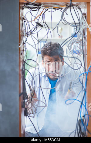 Electrician trying to untangle wires in repair concept Stock Photo