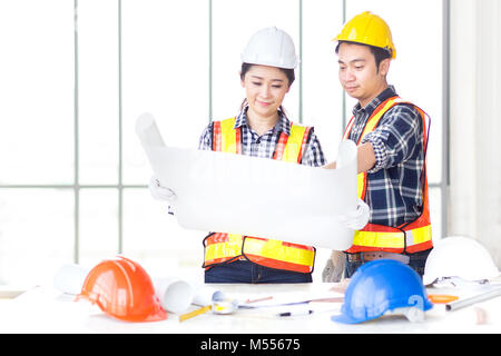 female engineer look and discuss with male engineer, team work, about drawing paper at work behind their desk Stock Photo
