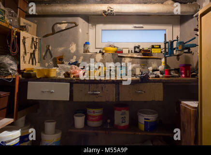 DUINO AURISINA, Italy - December 6, 2017: Very old dirty and messy garage workbench full of rusty tools, cans and boxes Stock Photo