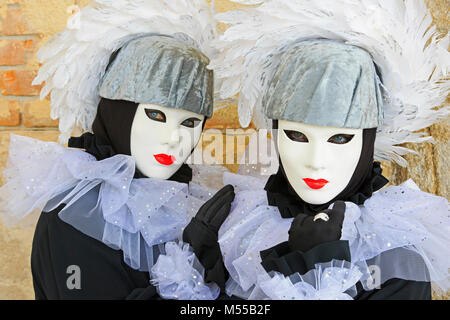 Twin sisters dressed like harlequins outside the Doge's Palace during the Carnival of Venice (Carnevale di Venezia) in Venice, Italy Stock Photo