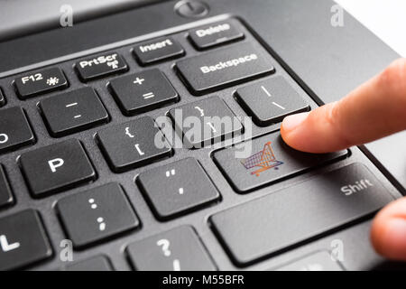 laptop keyboard with finger pressing shopping cart key Stock Photo