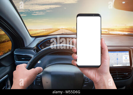 Driver keeps the phone while driving. Isolated screen for mockup. Modern car interior with navigation on board screen. Stock Photo