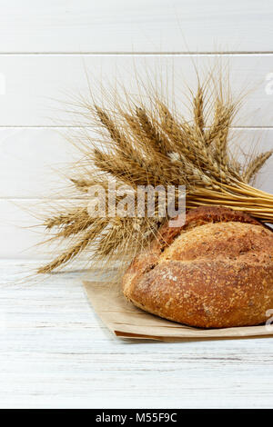 Bread and wheat on white wooden background. Stock Photo