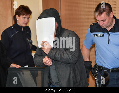 The defendant holds paper in front of his face and enters the courtroom with handcuffs during the trafficking trial at the district court in Frankfurt an der Oder, Germany 20 February 2018. The defendant drove the trafficking truck with 71 refugees. The Public's Prosecutors Office accuses the defendant of smuggling 20 people from the Iraq and Iran in August 2017 and 51 people from Syria and the Iraq in September from Romania to Germany. Photo: Patrick Pleul/dpa-Zentralbild/dpa Stock Photo