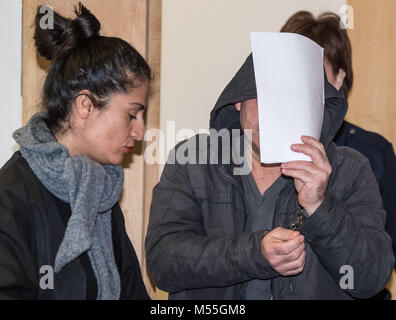 The defendant holds paper in front of his face and enters the courtroom with handcuffs, his lawyer Mehtap Ayhan on the left, during the trafficking trial at the district court in Frankfurt an der Oder, Germany 20 February 2018. The defendant drove the trafficking truck with 71 refugees. The Public's Prosecutors Office accuses the defendant of smuggling 20 people from the Iraq and Iran in August 2017 and 51 people from Syria and the Iraq in September from Romania to Germany. Photo: Patrick Pleul/dpa-Zentralbild/dpa Stock Photo