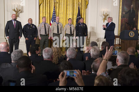 February 20, 2018 - Washington, District of Columbia, United States of America - United States President Donald J. Trump applauds District Attorney Investigator Chad Johnson, San Bernardino County District Attorney's Office(left), Detective Brian Olvera, San Bernardino Police Department(2nd left), Deputy Shaun Wallen, San Bernardino County Sheriff's Department(3rd left), Detective Bruce Southworth, San Bernardino County Sheriff's Department(3rd right), Corporal Rafael Ixco, San Bernardino County Sheriff's Department(2nd right) and Officer Nicholas Koahou, Redlands Police Department(right) as r Stock Photo