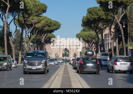 View down centre of Via di San Gregorio toward Constantine's Arch and the Coliseum with traffic and maritime pine trees either side, on warm sunny day Stock Photo