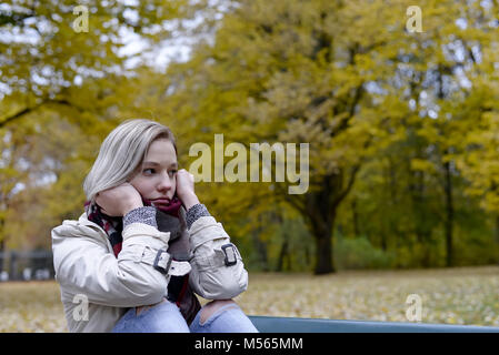 lonely young woman sitting on bench Stock Photo