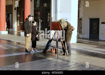 Photographer with a vintage glass plate wooden camera under dark cloth cape photographing people in Thessaloniki, Greece. Stock Photo
