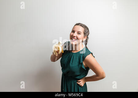 Eat fruits every day, close up isolated studio portrait of a woman eating banana Stock Photo