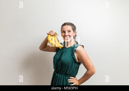 Happy charming woman holds banana fruits and looks away Stock Photo