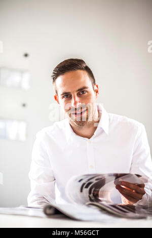 Portrait of young businessman analyzing brochure in office Stock Photo