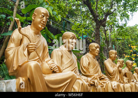 Golden Buddha statues along the stairs leading to the Ten Thousand Buddhas Monastery and landscape with green trees in the background in Hong Kong. Ho Stock Photo