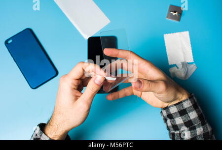 Man applying protective tempered glass to smart phone screen Stock Photo