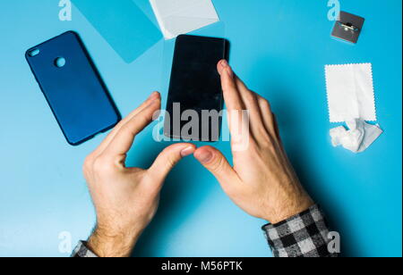 Man applying protective tempered glass to smart phone screen Stock Photo