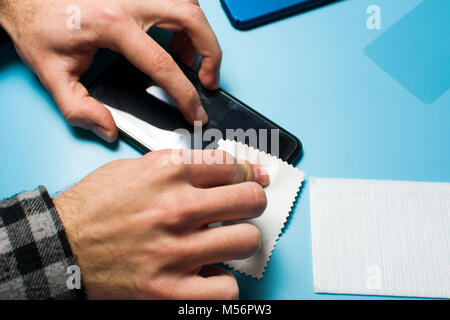 Man applying protective tempered glass to smart phone screen Stock Photo
