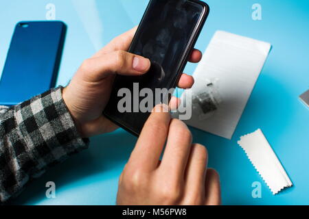 Man applying protective tempered glass to smart phone screen Stock Photo