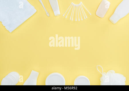 flat lay with cosmetic cream, body lotion, sponge, towel and cotton swabs, isolated on yellow Stock Photo
