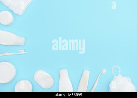 minimalistic background with lotion in bottles, cream in containers, toothbrushes, sponge and cotton swabs, isolated on blue Stock Photo