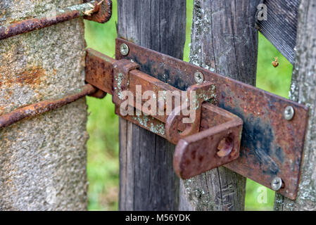Old rusted latch that ensures closing of wooden gate Stock Photo