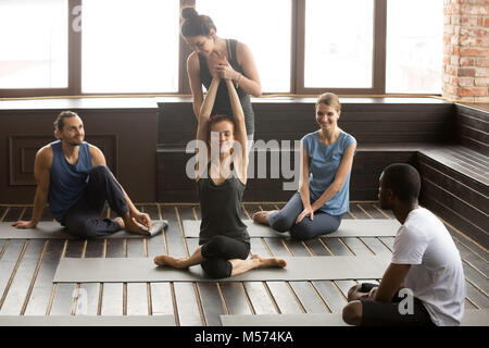 Female instructor helping woman to stretch teaching at group tra Stock Photo
