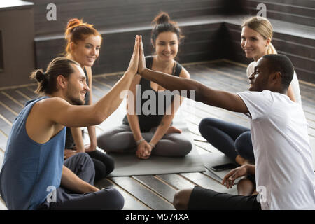 Smiling diverse yoga team members giving high-five at group trai Stock Photo