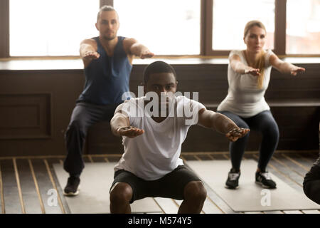 Young african-american man doing squat exercises at group fitnes Stock Photo