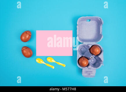 Easter composition with chocolate eggs with cream on blue background with space for text. Stock Photo
