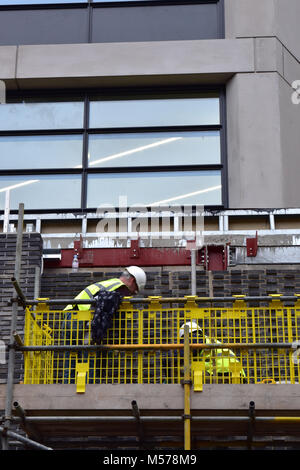 Construction workers on a building site in central london working safely wearing pipe and hard hats. Construction in london and the capital. Site city Stock Photo