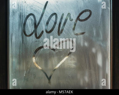 drawing of a heart and the word love on the wet glass of a window Stock Photo