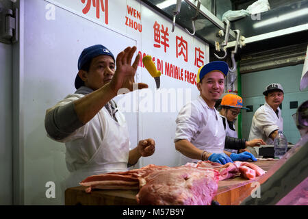 Rome, Italy: some butchers, intent on cutting meat, play skill games with the knife in a Chinese butcher's shop in Vittorio square Market Stock Photo