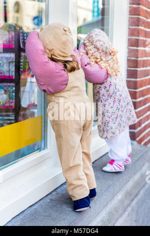 Boy and girl puppet peek through shop window Stock Photo