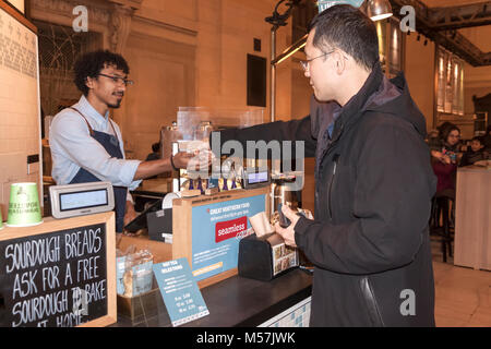 Male customer paying with coins for food/drink in Grand Central Station's Great Northern Food Hall food court. Stock Photo