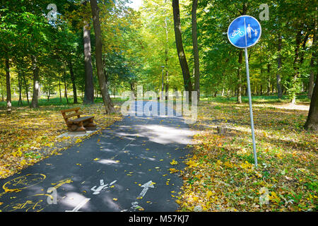 Bicycle path and a footpath with warning sign in autumn park. Stock Photo