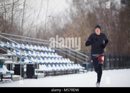 Image of running athlete in black clothes at stadium Stock Photo