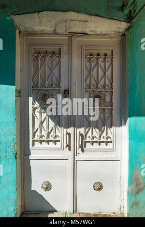 Old white door, turqoise weathered house wall Stock Photo