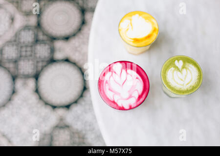 Two trendy beetroot lattes with latte art and flower petals on foam.an authentic girl dances on the street barefoot in a white T-shirt and a long flyi Stock Photo