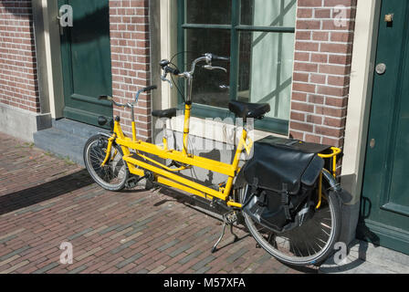 extended yellow bicycle with leather bag on the luggage rack placed against a window near a house  bagagerek Bewerken Stock Photo