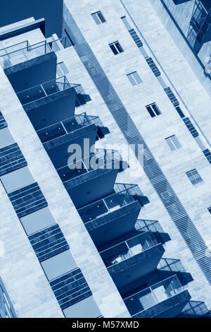 Diagonal composition - Blue Toned Image of  generic High rise apartment building front view with balcony facade.Conceptual image for Modern Architectu Stock Photo