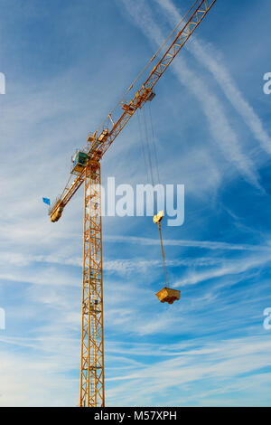 high yellow working crane on blue cloudy sky background Stock Photo