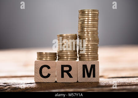 Closeup of CRM text written on wooden blocks with stacked coins Stock Photo