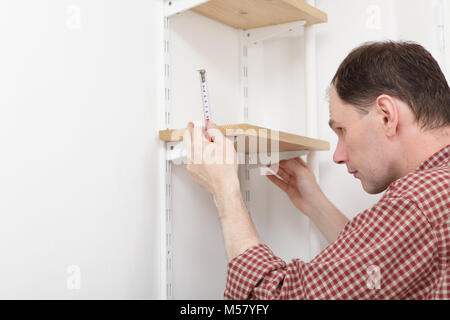 Man installing wooden shelves on brackets