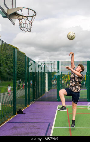 Young boy aged 13 plays basketball in Ballincollig Regional Park, County Cork, Ireland with copy space. Stock Photo