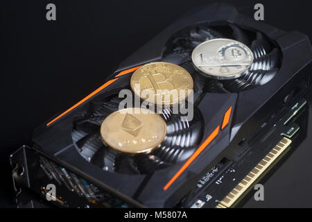 Cryptocurrency mining concept with bitcoins and ethereum on a videocard on black background. Stock Photo