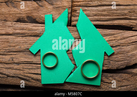 Closeup of rings on broken model house on wood representing relationship difficulties Stock Photo