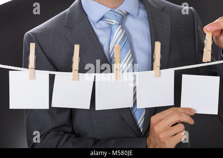 Closeup midsection of businessman pinning blank paper on clothesline Stock Photo