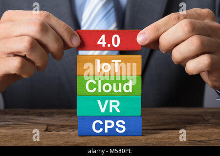 Closeup of hand building industry 4.0 concept with wooden blocks on wood Stock Photo