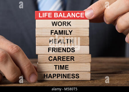 Closeup of businessman building life balance concept with wooden blocks on wood Stock Photo