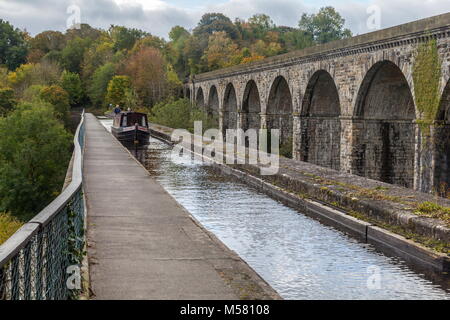 A narrow boat crosses from England into Wales across the Chirk Aqueduct during early Autumn. The Henry Robertson built Viaduct stands above the canal Stock Photo